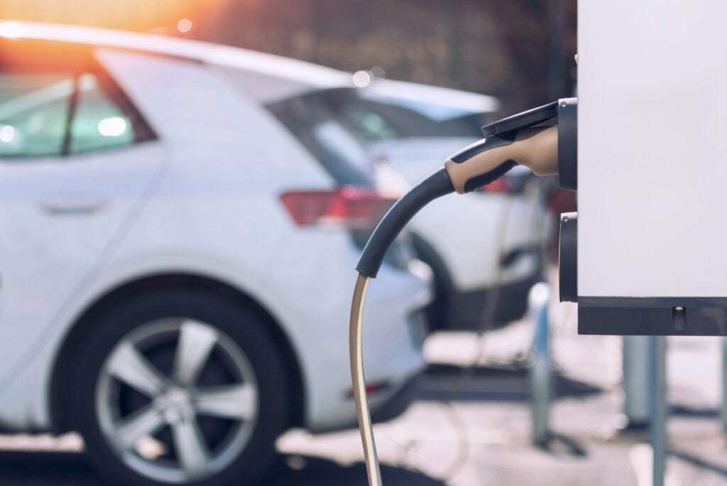 Car charging station with white electric car in the background.