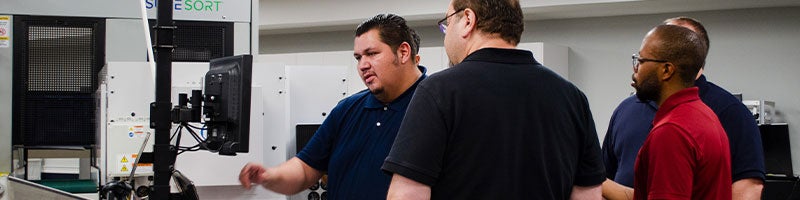 4 employees standing in front of a monitor