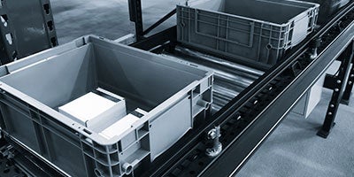 Gray containers placed on the conveyor belt